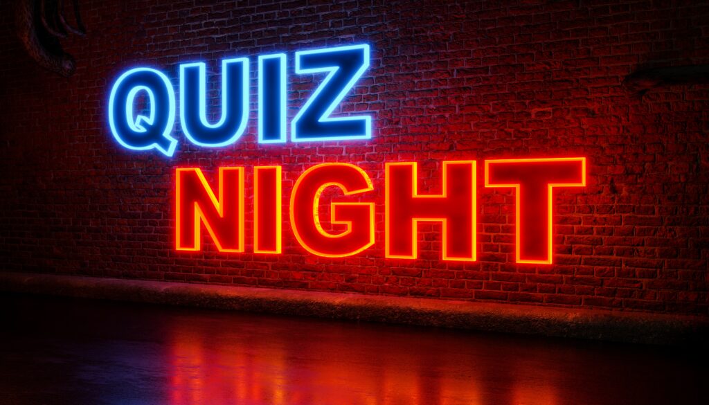 Quiz,Night.,Text,In,Orange,And,Blue,Illuminated,Letters.,Brickwall